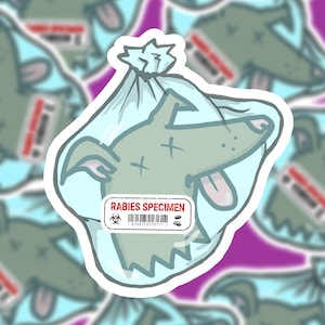 May include: A sticker featuring a cartoon dog in a plastic bag, labeled "RABIES SPECIMEN." The dog is gray with a pink tongue and a cross drawn on its face. The bag is light blue, and the sticker has a white border.