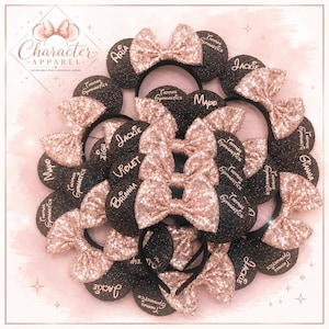 May include: A collection of black glittery headbands featuring rose gold sequined bows. Each headband displays the text Thomas Gymnastics and various names such as Aria, Jackie, Mapo, Violet, Brianna, and Gianna in rose gold script lettering.