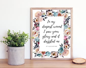 May include: A framed print with a watercolor floral border and a quote by St. Augustine: "In my deepest wound I saw your glory and it dazzled me."