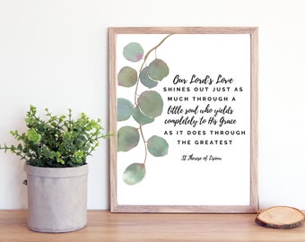 May include: A framed print with a watercolor illustration of eucalyptus leaves. The print features a quote by St. Therese of Lisieux: "Our Lord's Love shines out just as much through a little soul who yields completely to His Grace as it does through the greatest."