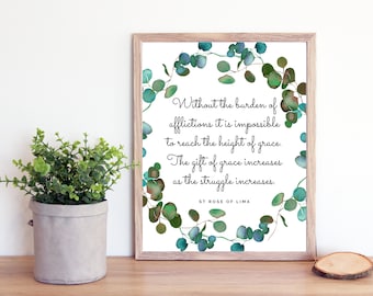 May include: A printable quote by Saint Rose of Lima, framed in a light wood frame. The quote reads "Without the burden of afflictions it is impossible to reach the height of grace. The gift of grace increases as the struggle increases." The quote is surrounded by a watercolor wreath of eucalyptus leaves.