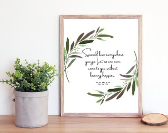 Könnte beinhalten: Ein gerahmter Druck mit einer Aquarell-Illustration eines Blattkränzchens. Das Zitat "Verbreite Liebe überall, wo du hingehst. Lass niemanden jemals zu dir kommen, ohne glücklicher zu gehen." steht in der Mitte des Kranzes. Das Zitat wird  St. Teresa von Kalkutta zugeschrieben.