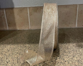 May include: A roll of gold glitter ribbon. The ribbon is a sheer, shimmery fabric with a subtle sparkle.