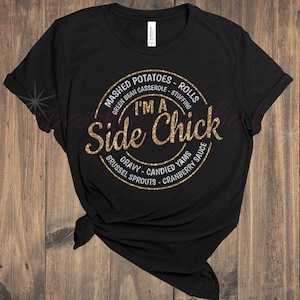 May include: Black t-shirt with a gold glitter design that says "I'm a Side Chick" with a list of Thanksgiving side dishes around the text.