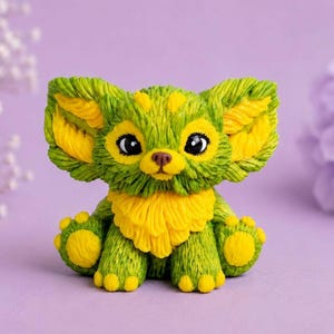 May include: A small, textured figurine of a creature with large, pointed ears, rendered in vibrant green and bright yellow. The figure features a dense, fur-like surface pattern, large black eyes, a small brown nose, and rounded paws with yellow pads.