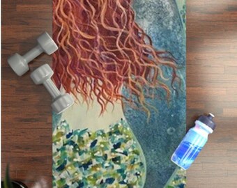 May include: A yoga mat with a colorful illustration of a mermaid with flowing red hair and a blue tail. The mermaid is wearing a green and blue patterned top.