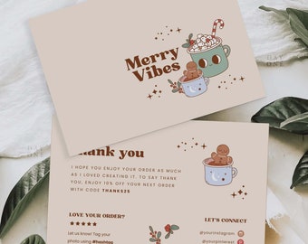 May include: A thank you card with a festive winter theme. The card features a gingerbread person and a mug of hot chocolate with marshmallows. The text on the card reads "Merry Vibes" and "Thank You".