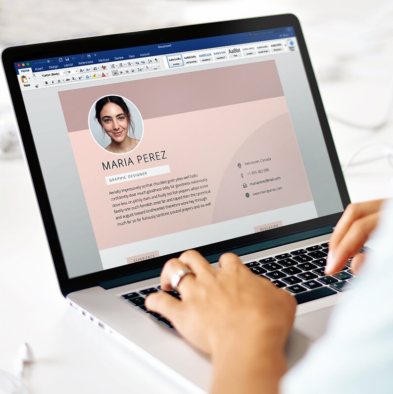 May include: A laptop computer screen displays a resume for Maria Perez, a graphic designer. The resume is on a pink background with a headshot of Maria Perez in the top left corner. The resume includes her contact information and a brief summary of her skills and experience.