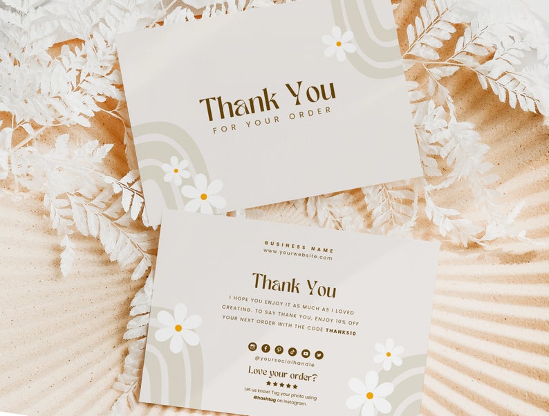 May include: Two thank you cards with a light brown background and white daisies. The top card says "Thank You for Your Order". The bottom card says "Thank You" and includes a business name, website address, and a discount code.