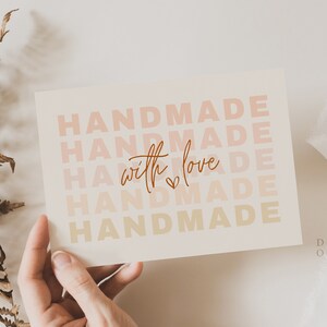 May include: A white card with the text "HANDMADE" repeated five times in a gradient of pink, orange, and yellow. The text "with love" is written in cursive in the center of the card with a small heart symbol.