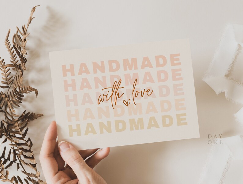 May include: A white card with the text "HANDMADE" repeated five times in a gradient of pink, orange, and yellow. The text "with love" is written in cursive in the center of the card with a small heart symbol.