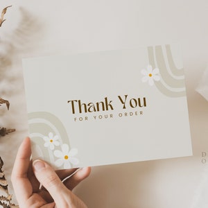 May include: A white thank you card with brown text that says "Thank You for Your Order". The card has a brown and white abstract design with white flowers.