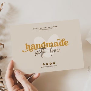 Op de afbeelding: Een beige kaart met de tekst "YOUR BUSINESS NAME" en een websiteadres. De kaart bevat ook de tekst "handmade with love" in gouden kleur met een gestileerde hartvorm achter de tekst. Op de onderkant van de kaart staan ​​social media-pictogrammen.
