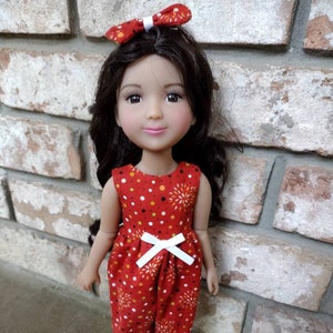 May include: A doll wearing a red and white jumpsuit with a white bow at the waist. The doll has brown hair and brown eyes. The doll is wearing white shoes.