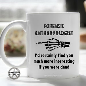 May include: White ceramic coffee mug with a black graphic that says "Forensic Anthropologist" and a skeleton hand pointing to the right. The text below the graphic says "I'd certainly find you much more interesting if you were dead." The text at the bottom of the mug says "@SilverSpurMercantile".