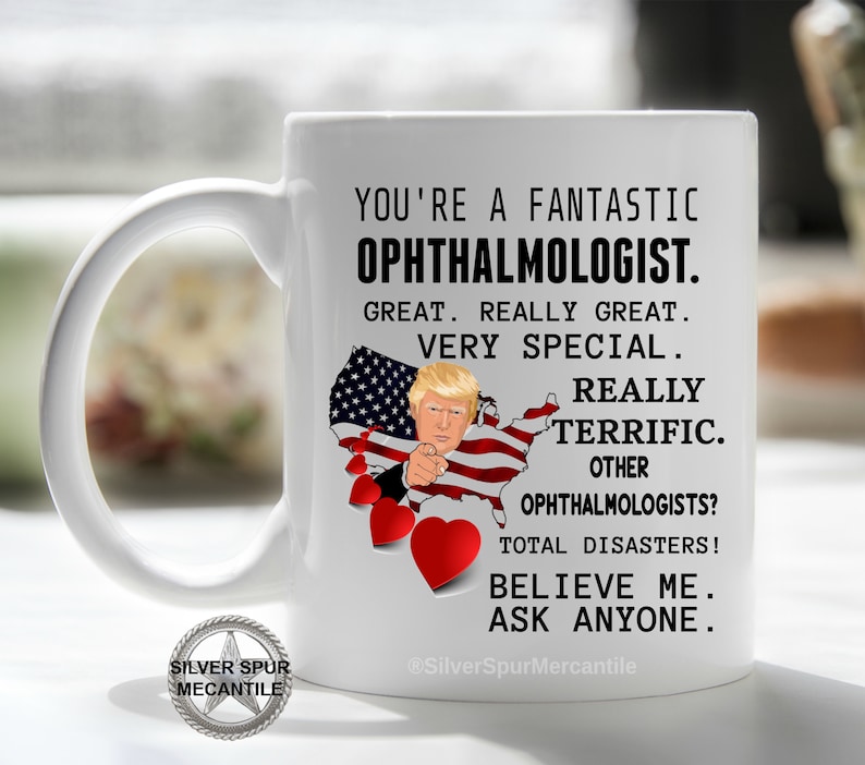 Pu&ograve; includere: Una tazza da caff&egrave; in ceramica bianca con un messaggio divertente sugli oculisti. La tazza presenta un'immagine di cartone animato di Donald Trump che punta verso lo spettatore con un cuore rosso e una bandiera americana sullo sfondo. Il testo dice: "Sei un fantastico oculista. Grandioso. Davvero grandioso. Molto speciale. Davvero fantastico. Altri oculisti? Disastri totali! Credimi. Chiedi a chiunque."