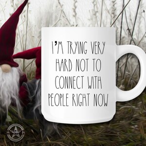 May include: White ceramic coffee mug with black text that reads "I'm trying very hard not to connect with people right now".