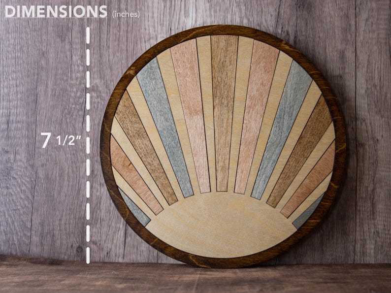 May include: A round wooden decorative piece with a sunburst design. The piece is 7 1/2 inches in diameter. The sunburst features alternating wooden panels in shades of brown, pink, and blue, set within a dark brown frame.