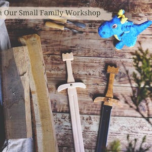 May include: Wooden toy swords with a light wood finish and a black blade, alongside a blue plush dragon toy. The image includes the text "From Our Small Family Workshop" and is set on a rustic wooden surface.