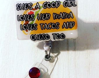May include: A white badge reel with a red gem and a clear plastic strap. The badge reel features a taco graphic and the text "She's a good girl loves her mama loves tacos and queso too."