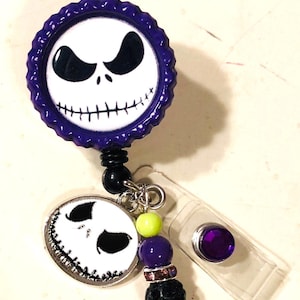 May include: A Jack Skellington themed retractable badge reel in purple and white. The reel features a Jack Skellington face design, with black beads, and a clear plastic clip.