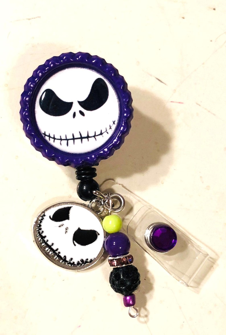 May include: A Jack Skellington themed retractable badge reel in purple and white. The reel features a Jack Skellington face design, with black beads, and a clear plastic clip.