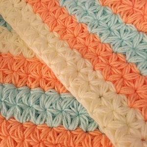 May include: A crocheted blanket with stripes of peach, light blue, and cream.