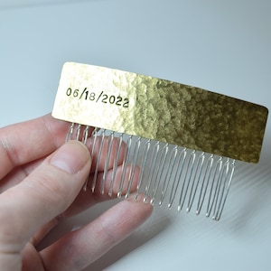 May include: Gold hair comb with a silver comb attached. The gold portion is engraved with the date "06/18/2022".