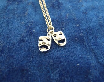 May include: A silver necklace with two silver charms in the shape of theater masks. One mask is smiling and the other is frowning.