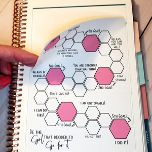 May include: A black and white motivational planner page with pink hexagonal goal stickers. The page features the text "Be the Girl that decided to Go for it" and includes motivational phrases like "Believe in yourself", "You are stronger than you think", "I am unstoppable", and "I did it!"