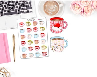 May include: A sheet of stickers featuring various illustrated mugs with holiday themes, including Santa hats and snowflake designs. Two larger mugs are also shown, one with a Santa hat and the other with string lights. A laptop, pen, and pink notebook are also visible.