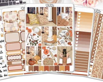 May include: A set of planner stickers with an autumn theme. The stickers feature illustrations of coffee, books, leaves, and a cosy living room. The stickers are in shades of brown, orange, and cream.