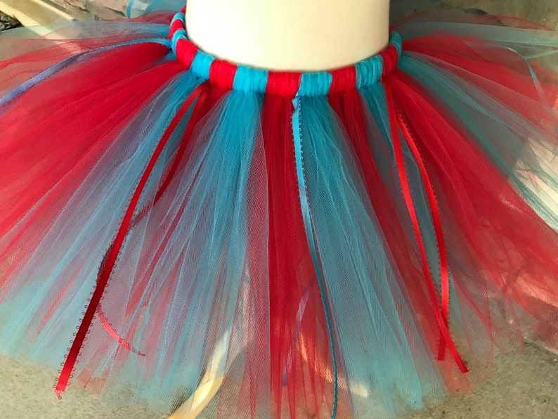 Puede incluir: Una vibrante falda tut&uacute; de tul rojo y azul claro. La cintura est&aacute; a rayas rojas y azul claro. Se adjuntan cintas rojas y azul claro a la falda, lo que se suma al dise&ntilde;o l&uacute;dico. Esta falda es adecuada para bailar o disfrazarse.