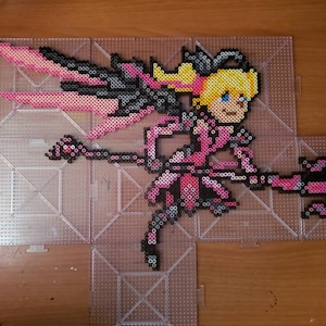 May include: A pink and black pixel art design of a female character with wings, a pink dress, and a weapon. The character is made of small plastic beads.
