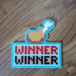 May include: A blue and white pixel art design of a chicken leg with the word "WINNER" written twice in red and black letters.
