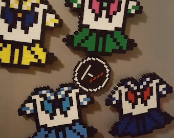 May include: A collection of pixel art magnets featuring a white-faced character with different colored outfits. The magnets are in blue, green, yellow, and red. A round sticker with the text "KALIFORNIA KOOL" is also visible.