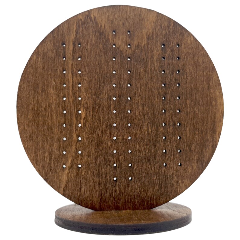 May include: A round wooden earring display stand with a brown stain. The stand has multiple holes for displaying earrings.
