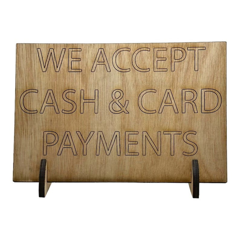 Może przedstawiać: Drewniany znak z tekstem "WE ACCEPT CASH & CARD PAYMENTS" w białych obramowanych literach.