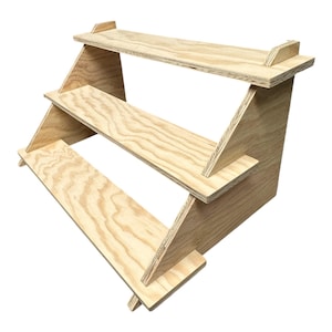 May include: A three-tiered wooden display stand made of plywood. The stand is unfinished and has a natural wood colour. It is perfect for displaying small items, such as jewellery, crafts, or cosmetics.