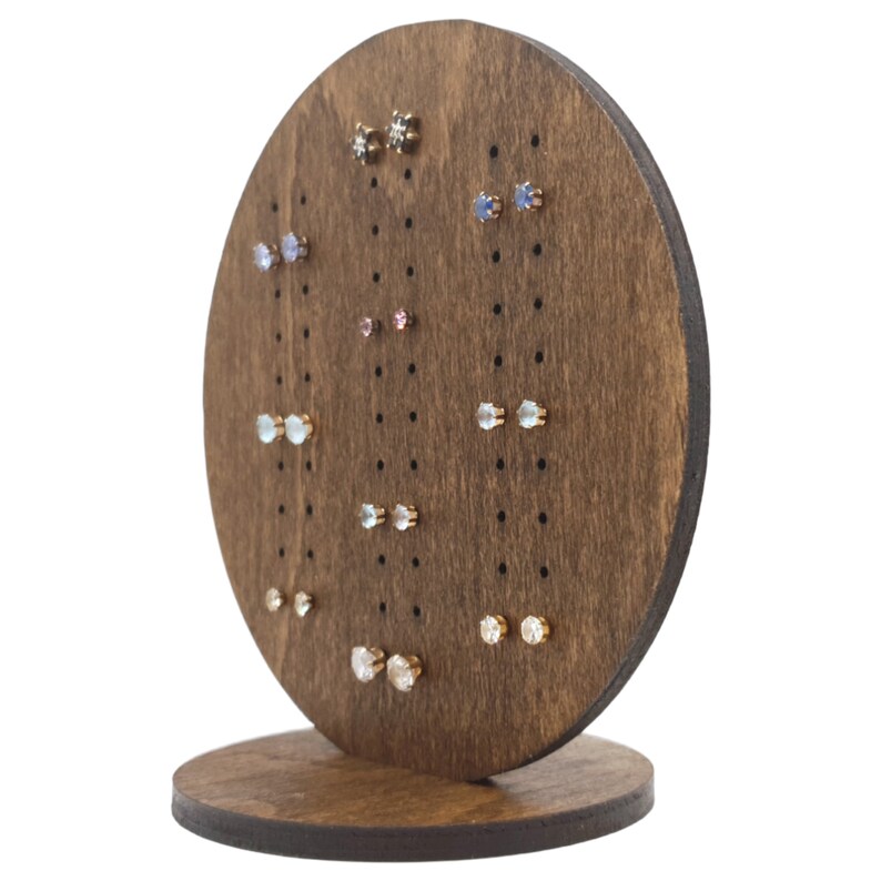 May include: A wooden earring display stand with a circular top and a base. The stand has multiple holes for holding earrings. The stand is filled with a variety of colourful earrings.