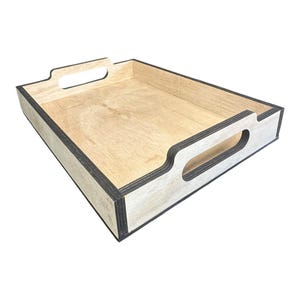 May include: A rectangular wooden tray with a light wood interior and dark edges. The tray has cut-out handles on each side. The tray is made of plywood and is suitable for serving food or organising items.