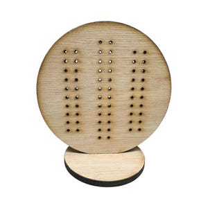 May include: A wooden peg board with three rows of holes, mounted on a round wooden base. The board is light brown and the holes are evenly spaced.