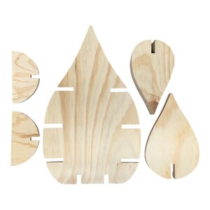 Peut inclure: Pi&egrave;ces en bois inachev&eacute;es en forme de goutte d'eau, dont une grande pi&egrave;ce centrale avec des fentes horizontales et plusieurs formes plus petites et compl&eacute;mentaires. Le grain du bois est visible, et les pi&egrave;ces sont con&ccedil;ues pour s'embo&icirc;ter.