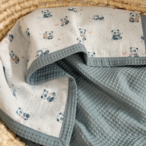 May include: A baby blanket with a white panda print and a blue waffle-weave texture. The blanket features a border with a gray trim. The panda print includes various panda poses and small stars.