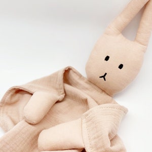 Puede incluir: Una manta de seguridad de conejito beige. El conejito tiene orejas largas, una cara negra simple y est&aacute; unido a una manta de muselina. El juguete est&aacute; dise&ntilde;ado para beb&eacute;s y ni&ntilde;os peque&ntilde;os.