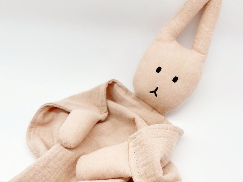 Puede incluir: Una manta de seguridad de conejito beige. El conejito tiene orejas largas, una cara negra simple y est&aacute; unido a una manta de muselina. El juguete est&aacute; dise&ntilde;ado para beb&eacute;s y ni&ntilde;os peque&ntilde;os.