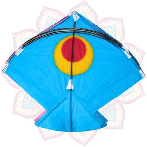 Op de afbeelding: Een helderblauwe vlieger met een cirkelvormig ontwerp in het midden, met een rood doel omringd door geel. De vlieger heeft een ruitvorm met een gebogen bovenkant en is afgewerkt met witte accenten en kwastjes.