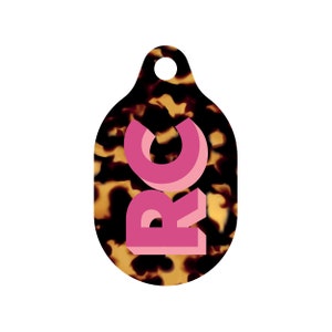 May include: A brown and black tortoiseshell patterned key chain with a pink 3D letter 'RC' on the front.