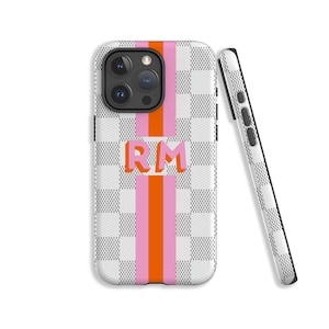 Puede incluir: Una funda de teléfono blanca con un patrón a cuadros y rayas rosas y naranjas. La funda tiene un "RM" en relieve en el centro.