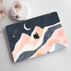 以下が含まれることがあります： 青い、ピンク、金色のデザインのラップトップスキン。山脈、三日月、流れ星、太陽が描かれています。デザインは星空の夜空を背景にしており、金色のグリッターのアクセントが施されています。